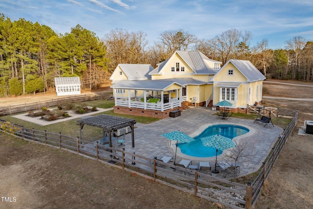 rear view of house with an outbuilding, metal roof, fence private yard, crawl space, and a fenced in pool