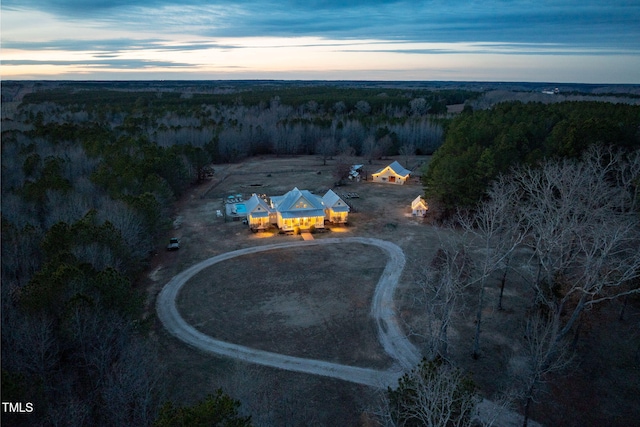 aerial view at dusk featuring a forest view