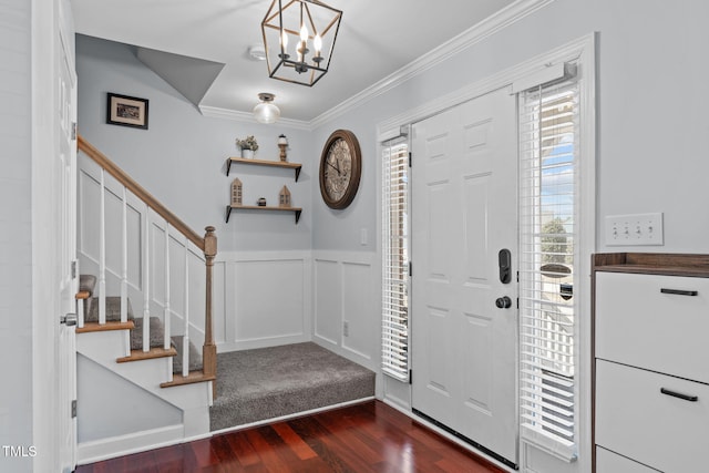 entrance foyer featuring a decorative wall, a wainscoted wall, dark wood-type flooring, stairs, and ornamental molding