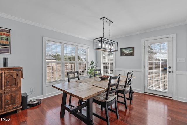 dining area featuring dark wood-style flooring, wainscoting, and crown molding