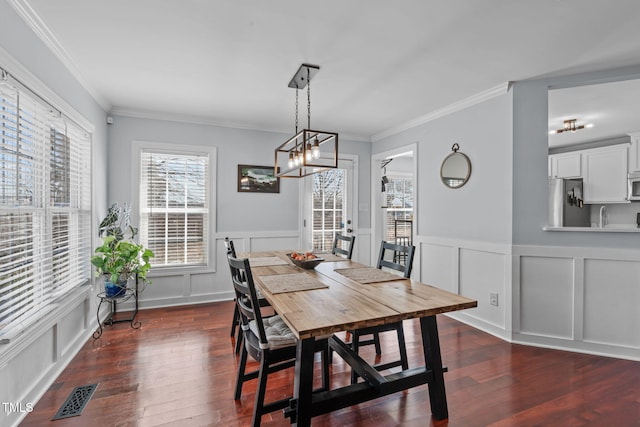 dining room with dark wood-style floors, visible vents, ornamental molding, and a decorative wall