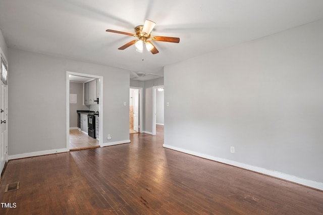 unfurnished living room featuring visible vents, baseboards, attic access, a ceiling fan, and wood-type flooring