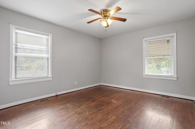 empty room featuring visible vents, ceiling fan, baseboards, and hardwood / wood-style floors