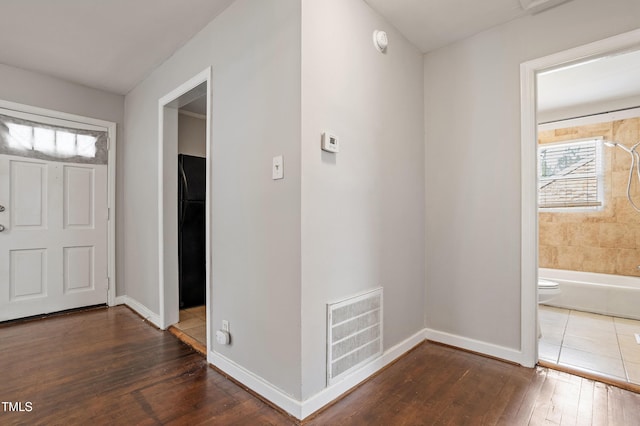 foyer entrance featuring hardwood / wood-style floors, baseboards, and visible vents