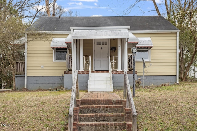 view of front of property featuring a front lawn and roof with shingles