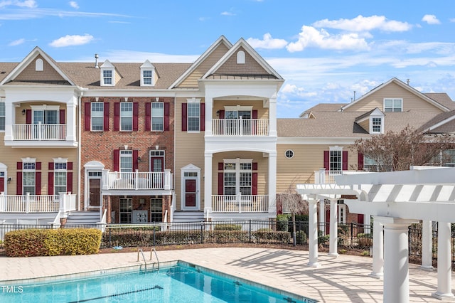 rear view of house featuring a patio area, a community pool, fence, and a pergola