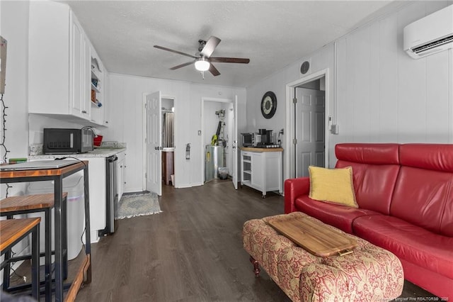 living area featuring dark wood-style floors, a wall unit AC, ceiling fan, and a textured ceiling