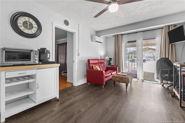 sitting room with a textured ceiling, a toaster, a ceiling fan, a wall mounted AC, and dark wood finished floors