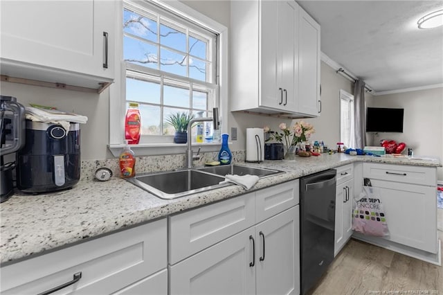 kitchen featuring black dishwasher, crown molding, light wood finished floors, white cabinets, and a sink