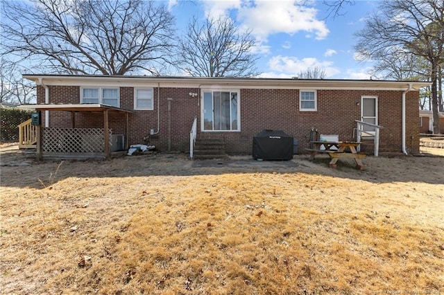 back of house with entry steps, brick siding, and a lawn