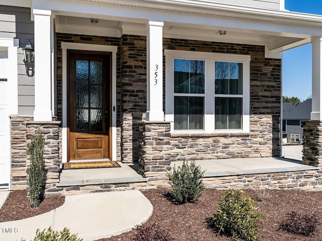 doorway to property featuring a porch and stone siding