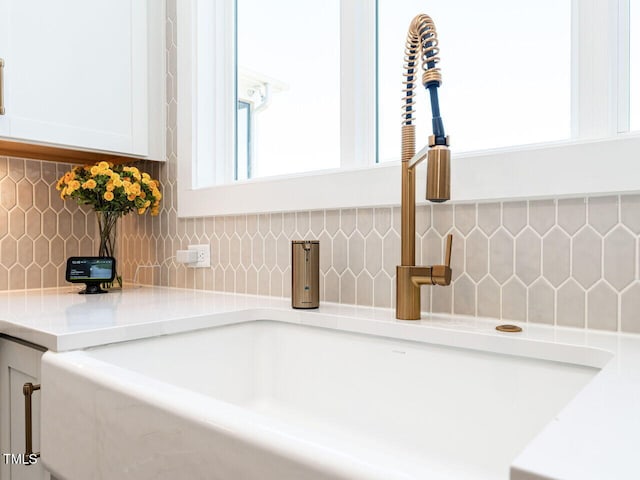 room details with light countertops, tasteful backsplash, a sink, and white cabinetry