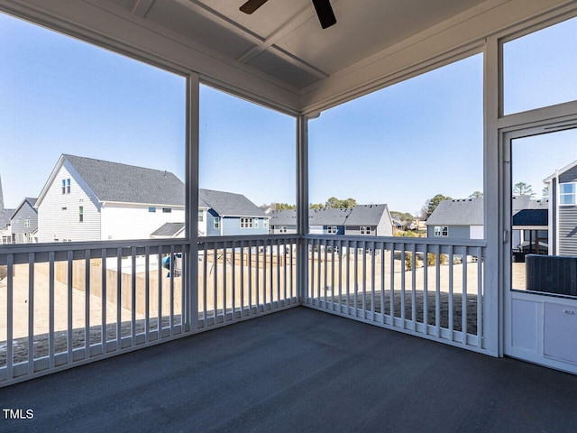 unfurnished sunroom with ceiling fan and a residential view