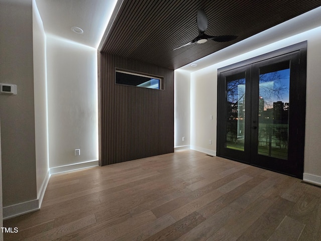 unfurnished room featuring baseboards, wood finished floors, and french doors