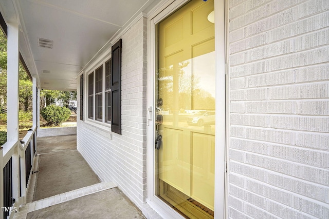 entrance to property featuring visible vents and brick siding