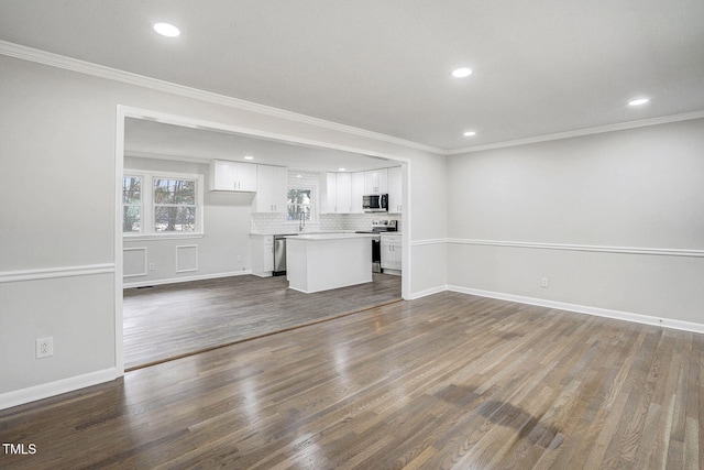 unfurnished living room with baseboards, recessed lighting, dark wood finished floors, and crown molding