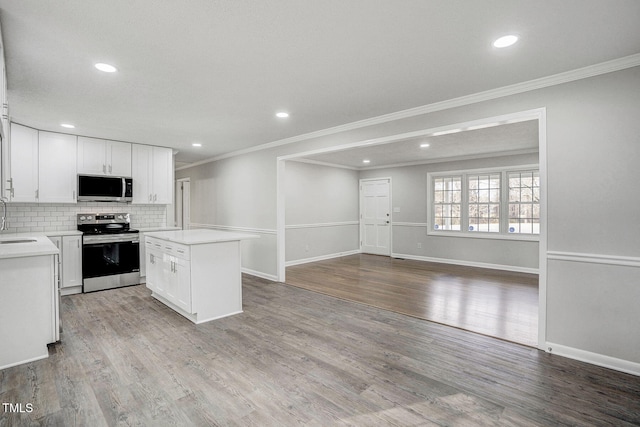 kitchen with appliances with stainless steel finishes, open floor plan, light countertops, and white cabinetry