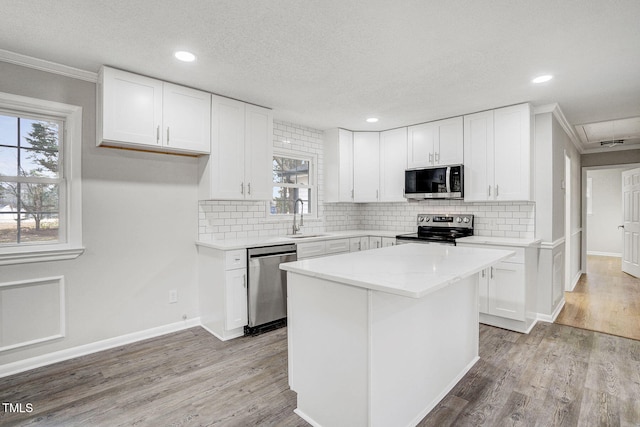 kitchen featuring a sink, appliances with stainless steel finishes, a center island, and white cabinets