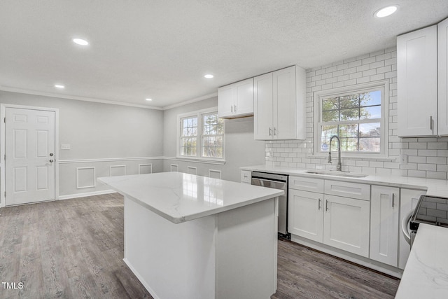 kitchen featuring appliances with stainless steel finishes, a center island, white cabinets, and a sink