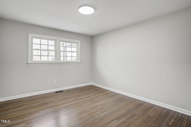 unfurnished room with dark wood finished floors, visible vents, and baseboards