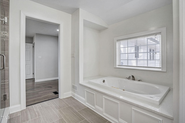 full bath featuring visible vents, a shower stall, a bath, and baseboards