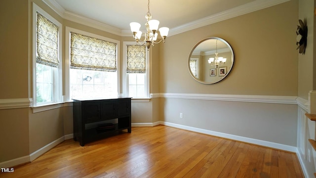 unfurnished dining area featuring baseboards, light wood-style floors, a chandelier, and ornamental molding