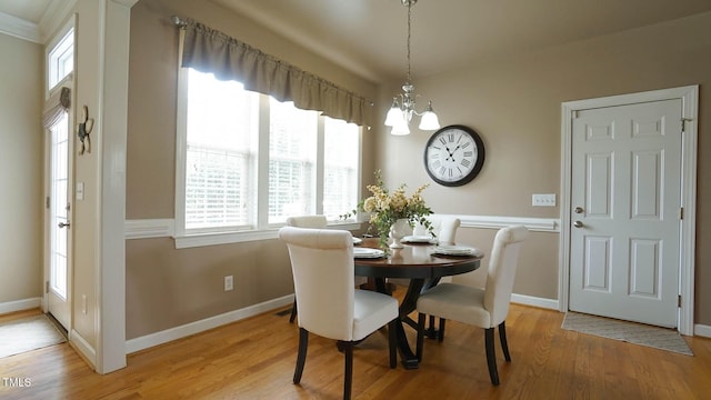 dining room with a notable chandelier, light wood-type flooring, and baseboards