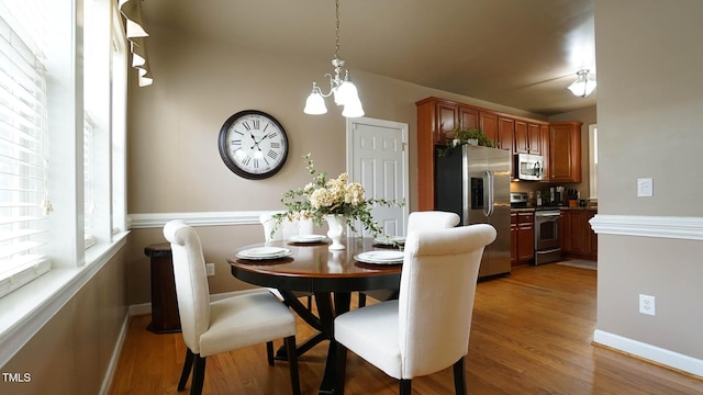 dining space featuring baseboards, a chandelier, and light wood finished floors
