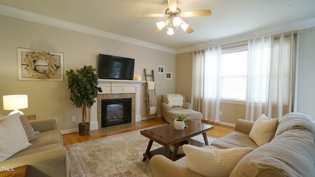 living room with light wood finished floors, a fireplace, baseboards, and ornamental molding