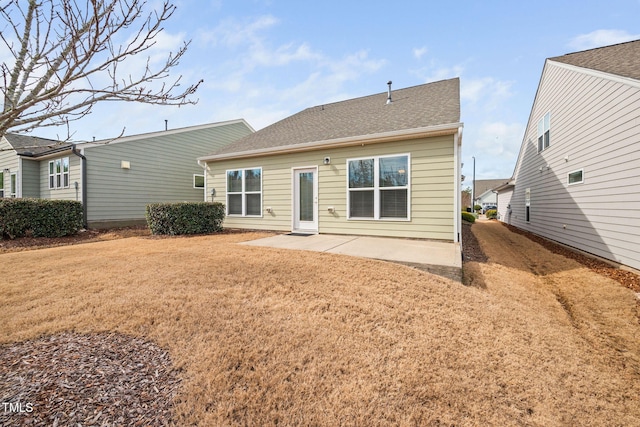 rear view of property with roof with shingles, a lawn, and a patio area