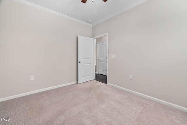 empty room with carpet, crown molding, baseboards, and ceiling fan