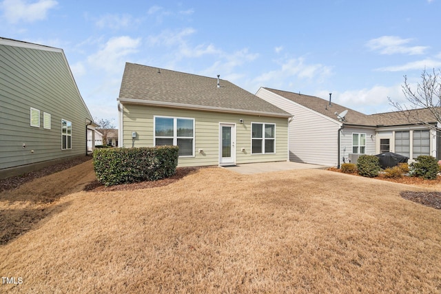 back of house with a yard, roof with shingles, and a patio