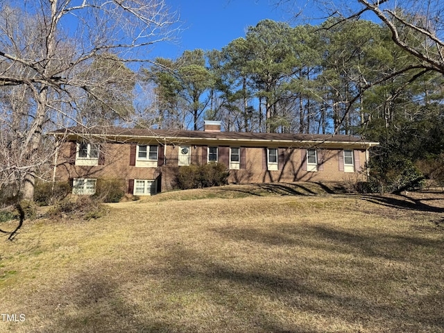 single story home with a chimney, a front lawn, and brick siding