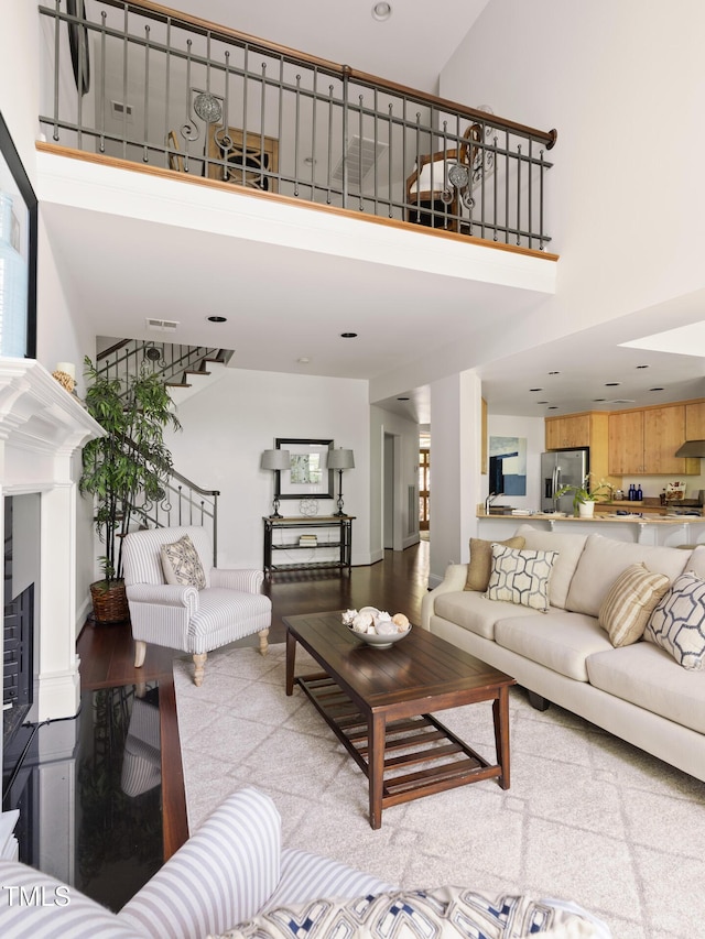 living area with visible vents, stairway, a high ceiling, and recessed lighting