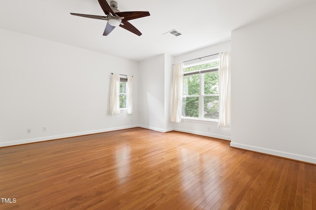 unfurnished room featuring light wood-style flooring, ceiling fan, baseboards, and visible vents