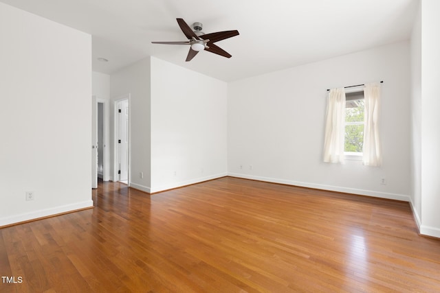 spare room featuring baseboards, light wood-type flooring, and a ceiling fan