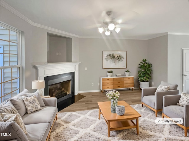 living room with a fireplace with flush hearth, crown molding, baseboards, and wood finished floors