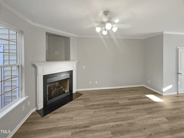 unfurnished living room with a fireplace with flush hearth, ornamental molding, baseboards, and wood finished floors