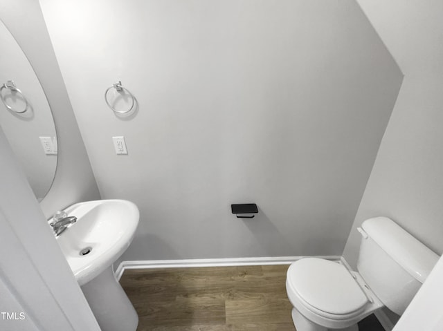 bathroom with toilet, baseboards, and wood finished floors