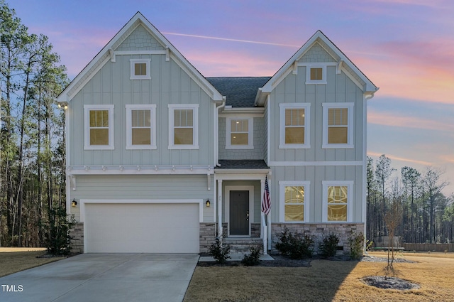 view of front of house with roof with shingles, concrete driveway, board and batten siding, a garage, and stone siding