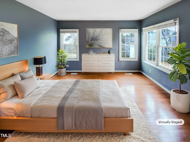 bedroom featuring light wood finished floors, baseboards, and visible vents