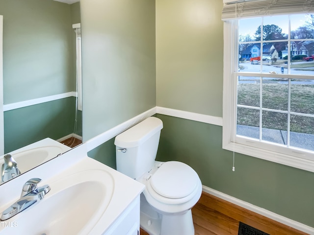 bathroom with visible vents, baseboards, toilet, wood finished floors, and vanity