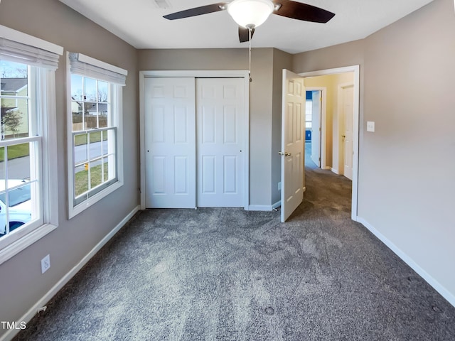 unfurnished bedroom with baseboards, dark colored carpet, and a closet