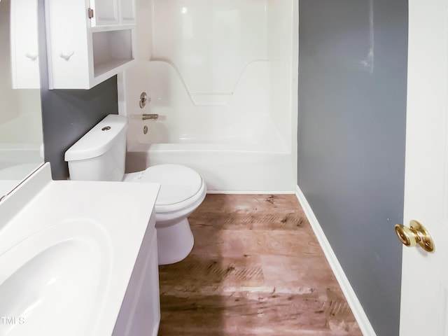 bathroom featuring toilet, washtub / shower combination, vanity, wood finished floors, and baseboards