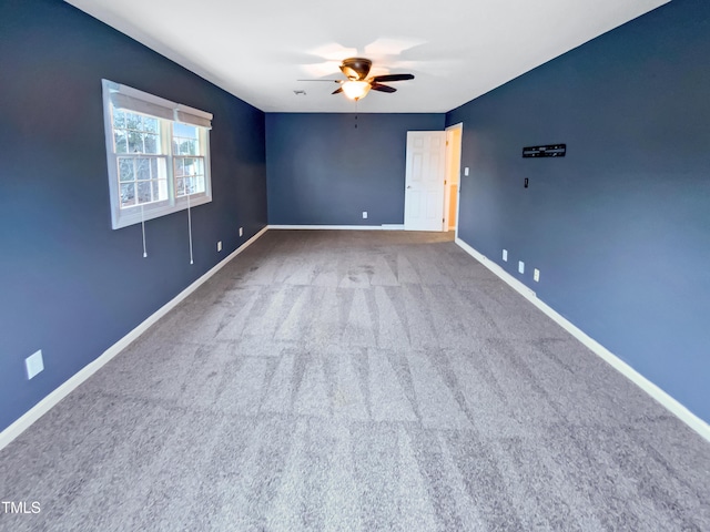 carpeted spare room featuring ceiling fan and baseboards