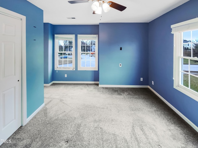 empty room featuring a wealth of natural light, visible vents, and baseboards