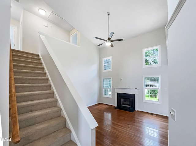 5317 Tifton Dr, Raleigh, NC 27610 - staircase featuring a towering ceiling, wood finished floors, a ceiling fan, and a fireplace with flush hearth