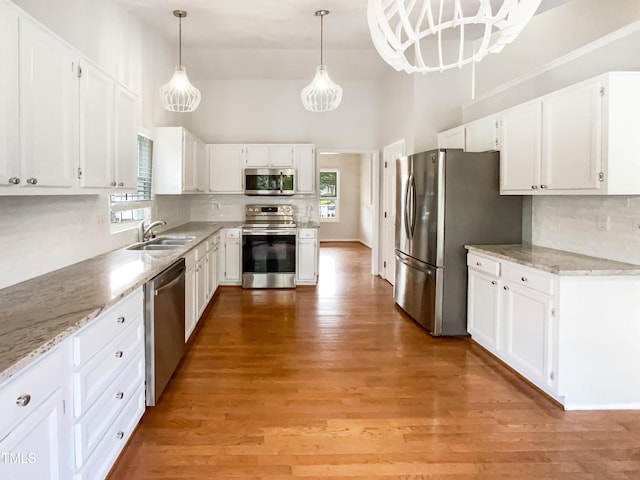 5317 Tifton Dr, Raleigh, NC 27610 - kitchen featuring appliances with stainless steel finishes, backsplash, white cabinets, and a towering ceiling