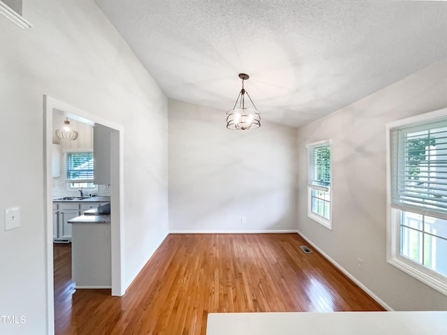 5317 Tifton Dr, Raleigh, NC 27610 - empty room featuring wood finished floors, plenty of natural light, a chandelier, and a textured ceiling