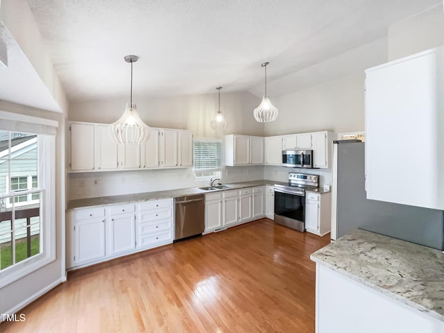 5317 Tifton Dr, Raleigh, NC 27610 - kitchen featuring appliances with stainless steel finishes, vaulted ceiling, plenty of natural light, and white cabinets